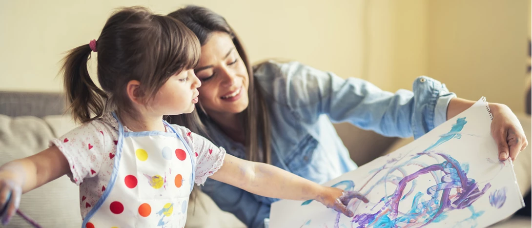 imagem de mãe e filha a pintar com tinta numa folha de papel